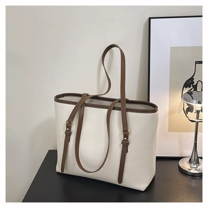 Detail of minimalist tote bag showing lychee grain leather and gold metal hardware