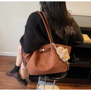 Detail einer großen braunen Wildleder-Tote-Bag mit süßem Plüsch-Hundeanhänger mit Perlen