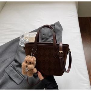 Detail of dark brown quilted suede bucket bag with leather strap and plush dog charm
