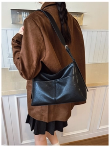 Detail of black leather crescent tote bag showing stitched texture and wide shoulder strap