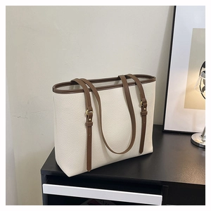 Detail view of large faux leather tote bag with adjustable brown straps and lychee texture