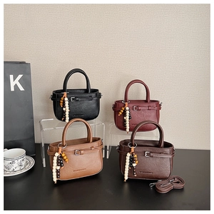 Detail of four colorful leather handbags with decorative bead charms and top handles