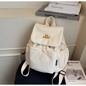 Detail of off-white canvas backpack featuring embroidered letters and side pocket