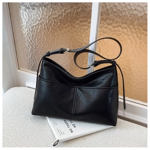 Close-up of black leather tote bag with vertical stitching and thin double straps