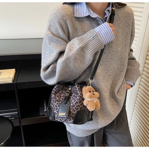Detail of leopard print bucket bag with drawstring closure and plush bear charm