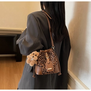 Detailed shot of leopard print bucket bag with leather strap and cute bear charm pendant