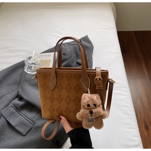 Close-up of caramel suede bucket bag with quilted rhombus pattern and cute dog pendant
