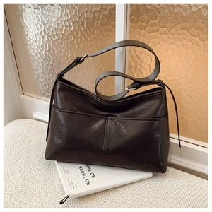Close-up of brown faux leather tote bag with front pocket and adjustable strap detail