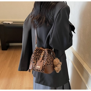 Detail view of leopard print bucket bag with leather trim and cute plush bear charm