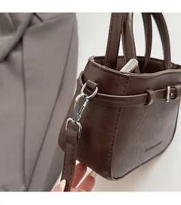 Close-up of deep brown lychee texture leather handbag with silver metallic hardware and buckle