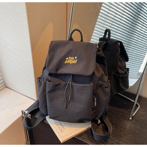Detail view of black drawstring backpack featuring vibrant yellow letter embroidery and pockets