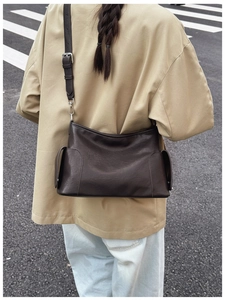 Détail du sac bandoulière en cuir marron foncé avec poches latérales et boucles argent