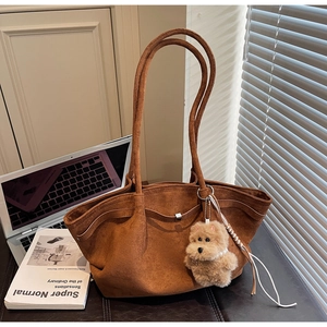 Detailed view of brown suede tote bag with plush puppy pendant and textured side straps