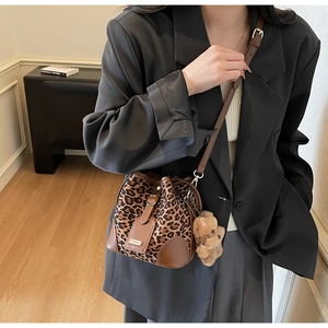 Detailed shot of leopard print bucket bag with brown leather trim and cute bear charm
