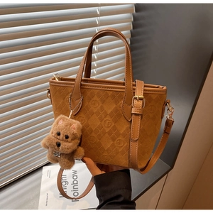 Close-up of brown suede bucket bag with F-pattern embossing and plush dog charm