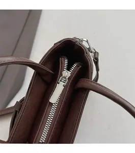 Detail shot of smooth silver metal zipper on premium dark brown leather square bag