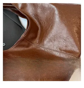 Detail view of brown vintage PU leather bag with soft pleated texture and white stitching