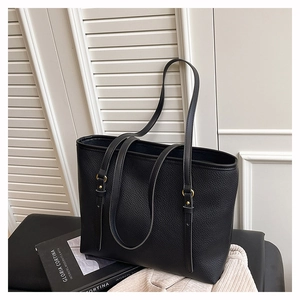 Close-up of black lychee texture tote bag with golden strap hardware and minimalist design