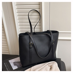 Close-up of black pebble leather tote bag with gold hardware and rivet details