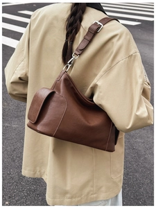 Détail d'un sac bandoulière marron foncé avec poche latérale et boucles argentées