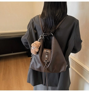 Detail of dark brown vintage faux leather backpack with metallic flower and bear charm