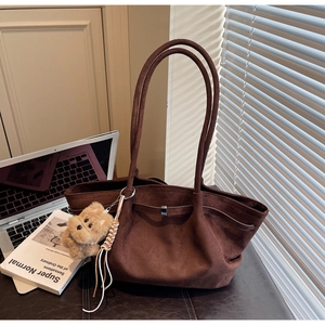 Detail of dark brown faux suede tote bag with plush dog charm and braided strap