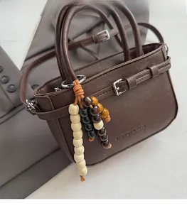 Close-up of handmade wooden bead charm in brown and cream on a leather handbag