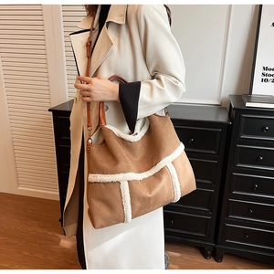 Detail of a large brown suede tote bag with white faux fur trim and adjustable strap