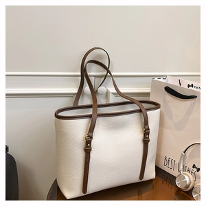 Detail of lychee pattern leather and dark brown handle with golden metal buckle on tote bag