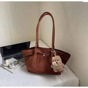 Brown faux suede tote bag with plush puppy charm on desk with office accessories