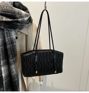 Detail of Matelassé pleated texture on black tote bag with elegant gold hardware accents
