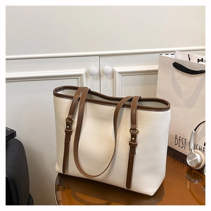 Detail of minimalist tote bag with off-white lychee texture and brown leather trim