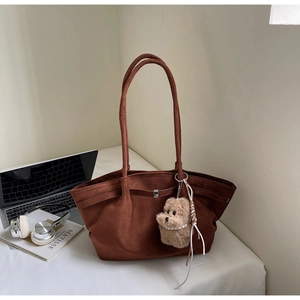 Detail of vintage brown tote bag with suede texture and cute plush dog pendant