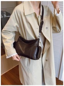 Détail du sac bandoulière en cuir marron foncé avec poche latérale et boucles argentées sur modèle