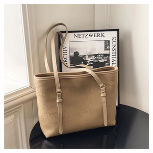 Close-up of the lychee grain leather texture and gold buckle on a khaki tote bag
