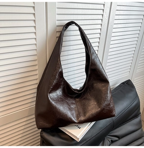 Detail of a glossy dark brown faux leather hobo bag with a spacious minimalist design
