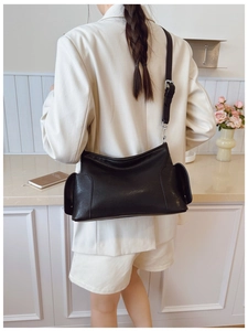 Détail d'un sac bandoulière minimaliste en cuir PU noir avec poches latérales et sangle
