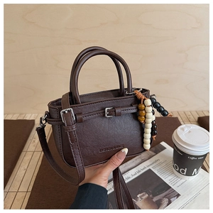 Brown mini crossbody bag with wooden beads and fashion embossing on wood background