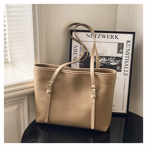 Close-up of khaki tote bag featuring lychee grain leather and adjustable buckle detail