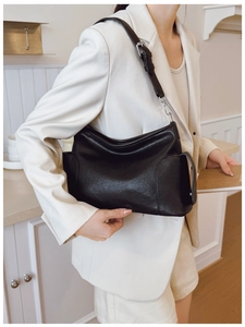 Détail de la bandoulière réglable avec boucle argentée sur un sac cabas en cuir noir mat