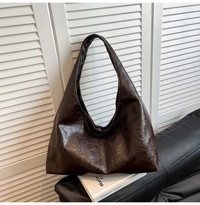 Detail of dark brown hobo bag in glossy oil wax leather with wide shoulder strap