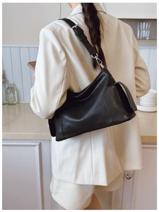 Détail du sac bandoulière en cuir noir minimaliste avec boucle argentée et sangle réglable