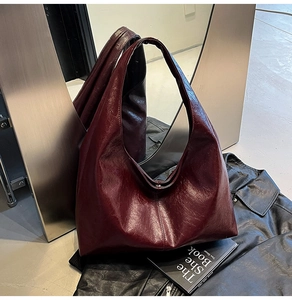 Macro shot of dark red glossy leather hobo bag with sleek shoulder strap texture