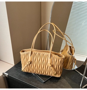 Close-up of khaki pleated matelassé leather shoulder bag with a stylish knotted strap