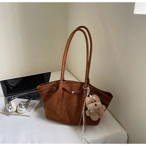 Nahaufnahme braune Wildleder-Tote-Bag mit Metallschnalle und süßem Plüschwelpen-Anhänger