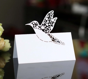 Detailed laser-cut hummingbird design on a white fold-over wedding place card