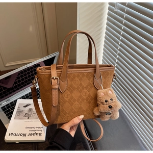 Detail of caramel suede bucket bag with diamond quilting and plush dog keychain