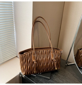 Detail of V-shaped pleated texture and drawstring knots on a brown tote bag