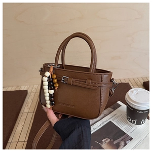 Brown faux leather handbag with adjustable strap and decorative beaded charm detail