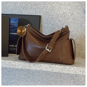 Détail du sac à bandoulière marron foncé brillant avec poches latérales et boucles